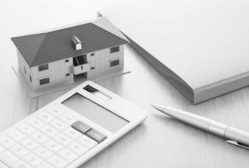 家の模型と電卓とファイルとペン